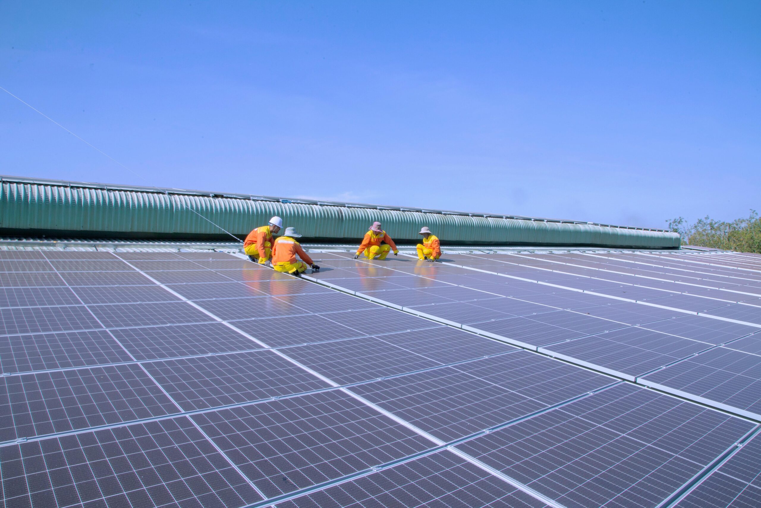Workers installing solar panels on a sunny rooftop, emphasizing renewable energy and sustainability.
