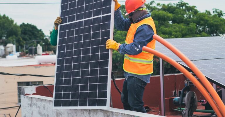 A technician in safety gear installs a solar panel on a rooftop, promoting renewable energy.